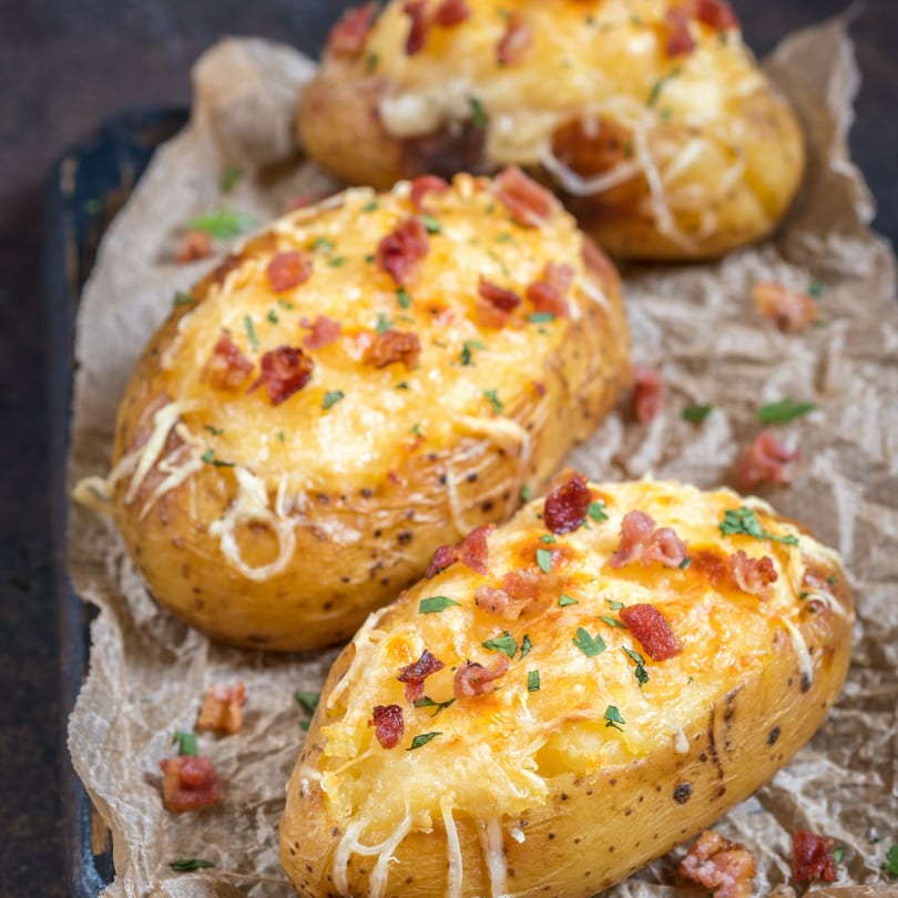 Three Maitais' loaded baked potatoes topped with melted cheese, bacon bits, and fresh parsley.